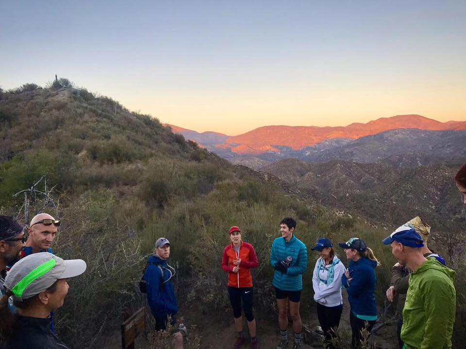 Cinda Brown (white jacket, blue hat) pauses with her group to watch a sunset over Southern California's San Gabriel Mountains at Band of Runners Trail Camp. PC: Dominic Grossman